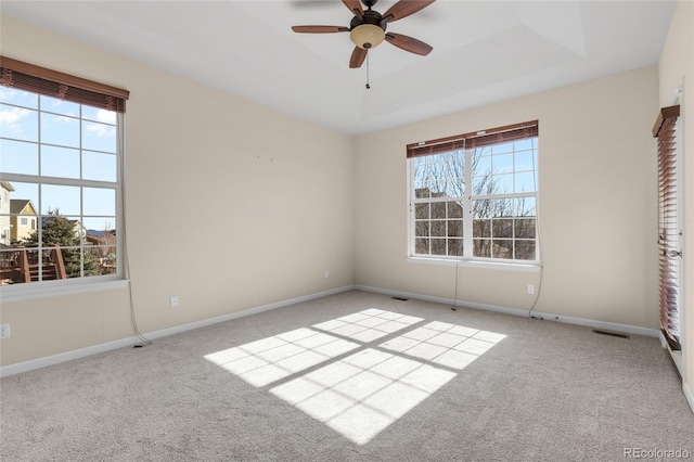 spare room featuring a tray ceiling, carpet, visible vents, and baseboards