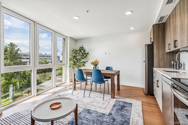 dining area featuring plenty of natural light, light wood-type flooring, and sink