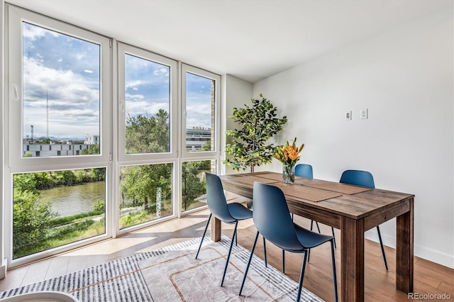 office area featuring a healthy amount of sunlight, a water view, and light hardwood / wood-style floors