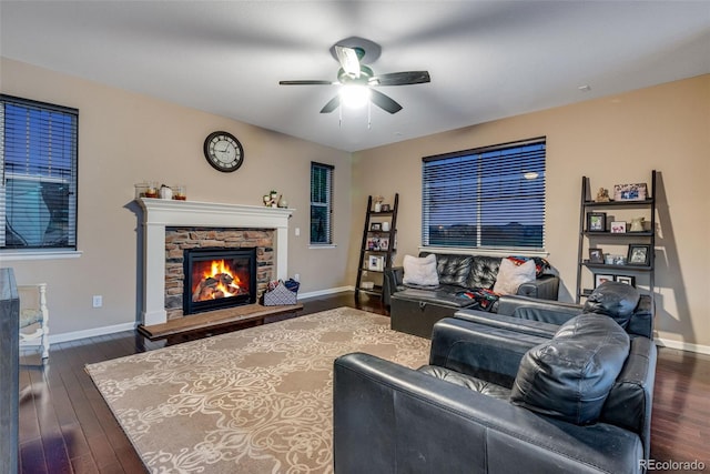 living room featuring ceiling fan, dark wood-type flooring, and a stone fireplace