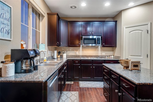 kitchen with dark hardwood / wood-style floors, appliances with stainless steel finishes, sink, and light stone counters