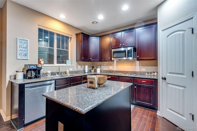 kitchen with light stone countertops, dark hardwood / wood-style floors, appliances with stainless steel finishes, and a kitchen island