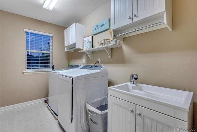 laundry room featuring washing machine and clothes dryer, sink, and cabinets