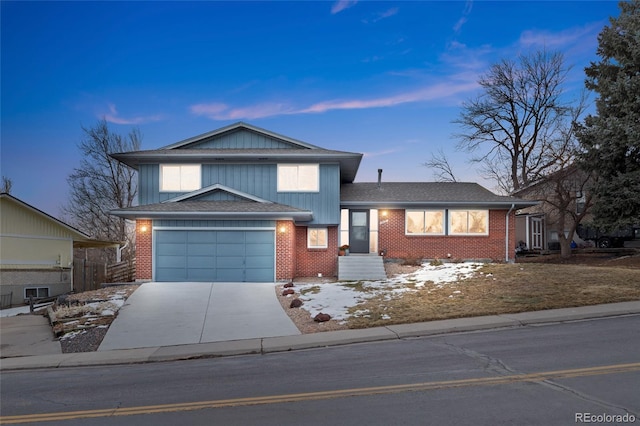 tri-level home with driveway, an attached garage, roof with shingles, and brick siding