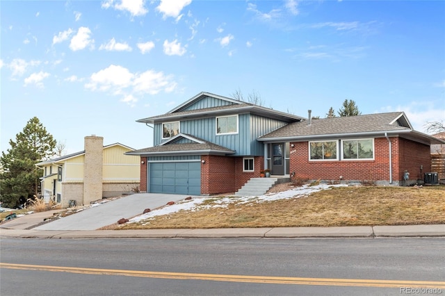 split level home with a garage, a shingled roof, concrete driveway, central AC, and brick siding