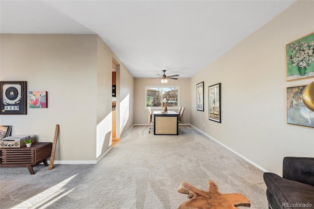 living area with ceiling fan, baseboards, and light colored carpet