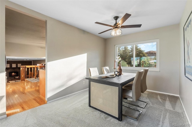 carpeted office space with a fireplace, baseboards, and a ceiling fan