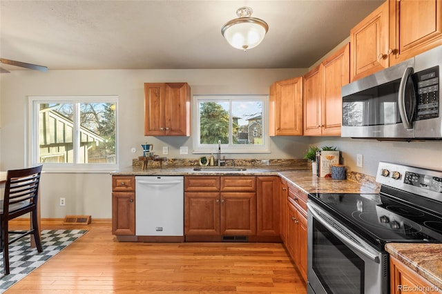 kitchen with visible vents, appliances with stainless steel finishes, a healthy amount of sunlight, a sink, and light wood-type flooring