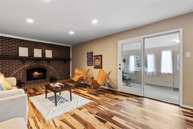 living room featuring recessed lighting, a fireplace, baseboards, and wood finished floors