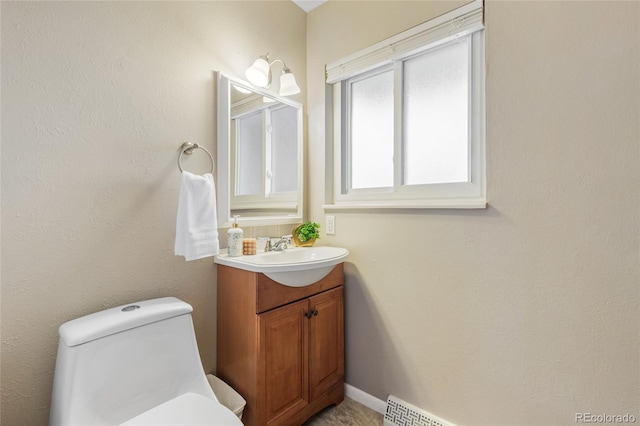 half bathroom with baseboards, vanity, and toilet