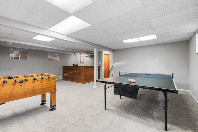 recreation room with a paneled ceiling, carpet, and baseboards