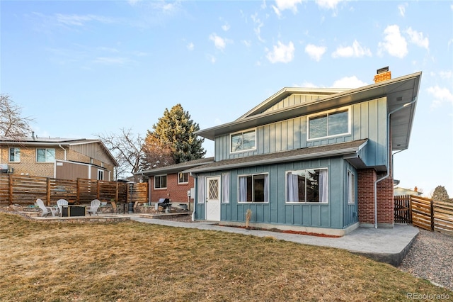 back of house featuring a chimney, board and batten siding, a patio area, and a fenced backyard