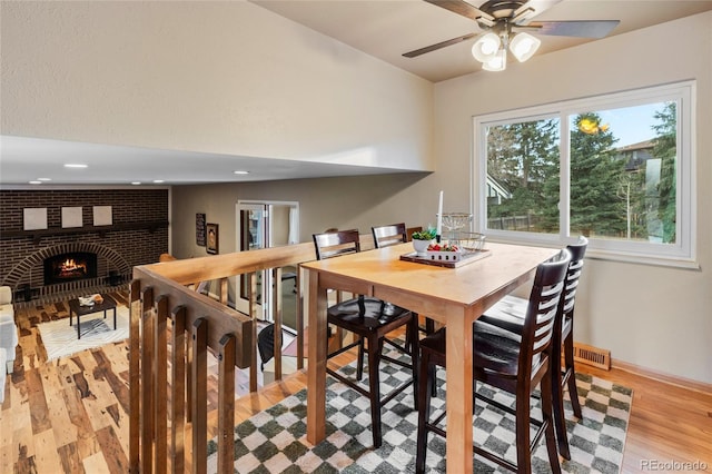 dining room featuring ceiling fan, light wood-style flooring, recessed lighting, a fireplace, and visible vents