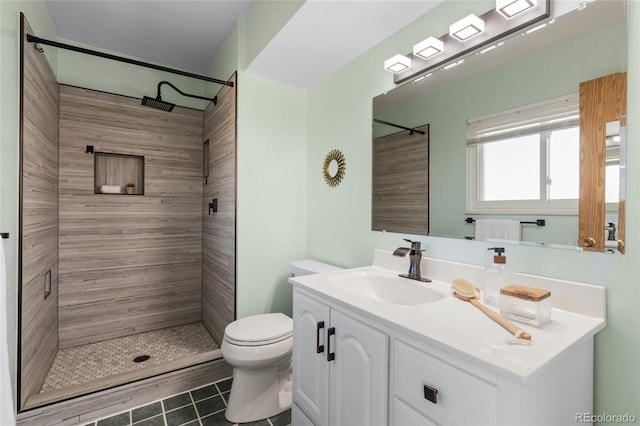 bathroom featuring toilet, tile patterned flooring, tiled shower, and vanity