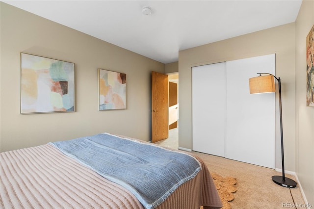 carpeted bedroom with a closet and baseboards