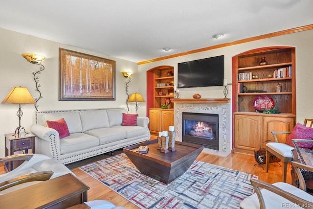 living room with light wood-style floors, a fireplace with flush hearth, and built in features