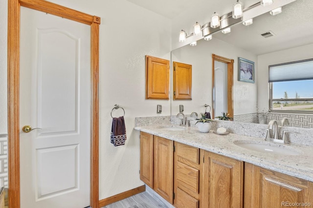 full bath with baseboards, visible vents, a sink, and double vanity