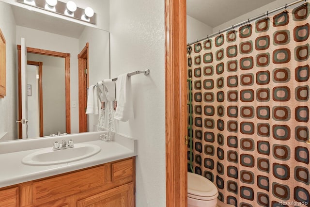 full bathroom with vanity, toilet, a shower with shower curtain, and a textured wall