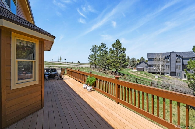 wooden terrace featuring a lawn, outdoor dining space, and a fenced backyard