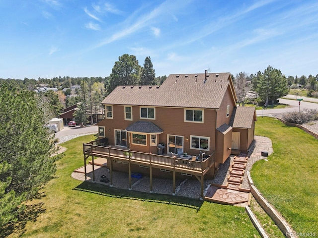 back of property with a lawn, a wooden deck, and roof with shingles