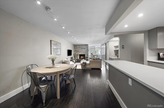 dining space featuring a large fireplace and dark wood-type flooring