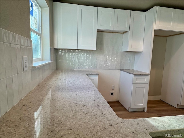 kitchen with white cabinets, tasteful backsplash, and light stone countertops