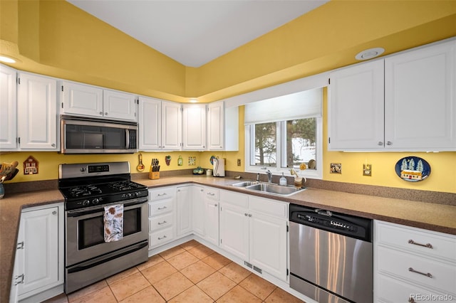 kitchen featuring light tile patterned flooring, appliances with stainless steel finishes, lofted ceiling, sink, and white cabinets