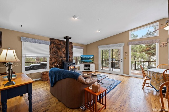 living room featuring hardwood / wood-style flooring, vaulted ceiling, a healthy amount of sunlight, and a wood stove