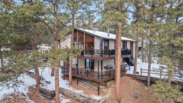 snow covered rear of property with a wooden deck