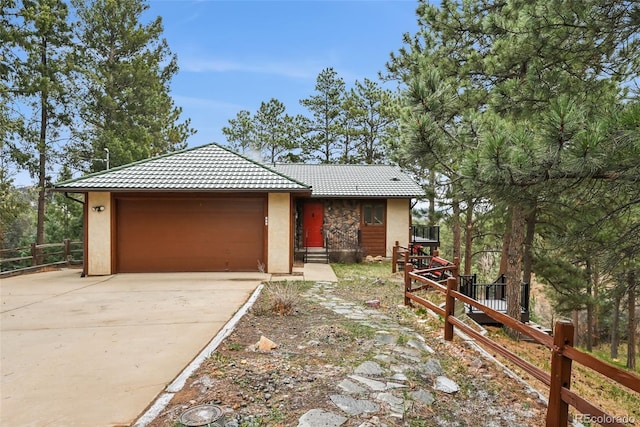 723 Eaton Rd, Palmer Lake, CO 80133 - view of front facade featuring fence, a tiled roof, stucco siding, an attached garage, and concrete driveway
