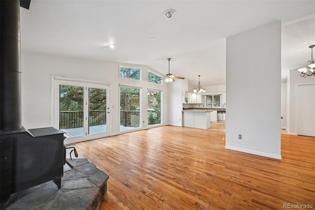 723 Eaton Rd, Palmer Lake, CO 80133 - living area with light wood-type flooring, vaulted ceiling, a wood stove, and ceiling fan with notable chandelier