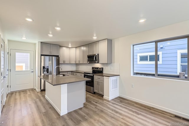 kitchen featuring an island with sink, appliances with stainless steel finishes, sink, and gray cabinetry