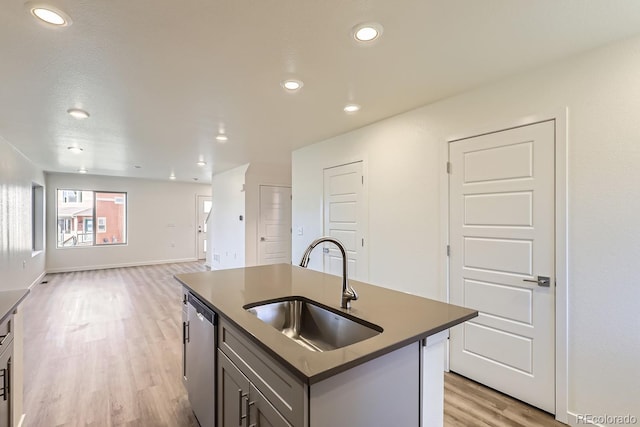 kitchen featuring sink, gray cabinetry, light hardwood / wood-style floors, a center island with sink, and stainless steel dishwasher