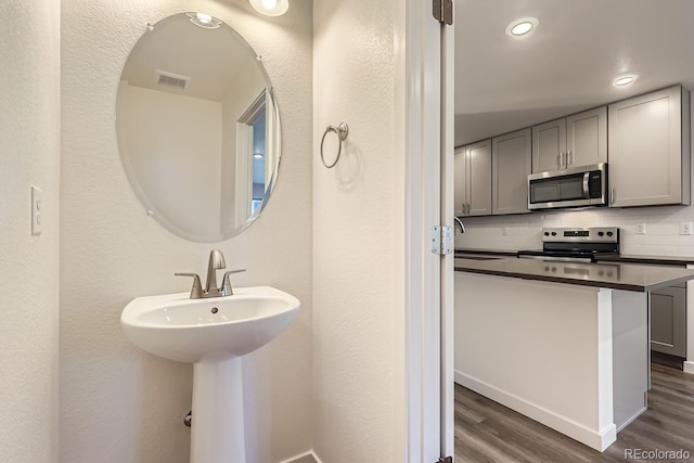 bathroom featuring hardwood / wood-style flooring, sink, and backsplash