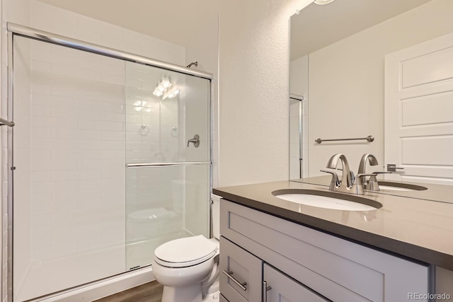 bathroom featuring walk in shower, wood-type flooring, toilet, and vanity