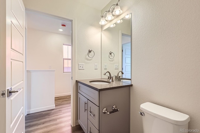 bathroom with wood-type flooring, toilet, and vanity