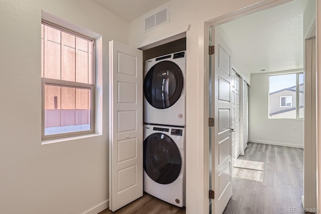 clothes washing area featuring stacked washer / dryer and wood-type flooring