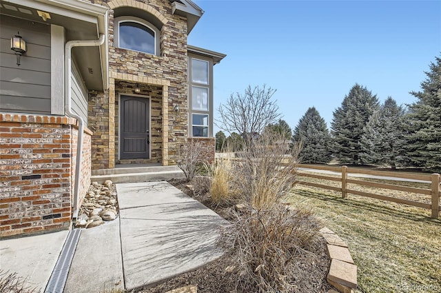 property entrance with stone siding and fence