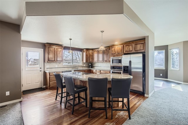 kitchen with appliances with stainless steel finishes, a breakfast bar area, backsplash, and a center island