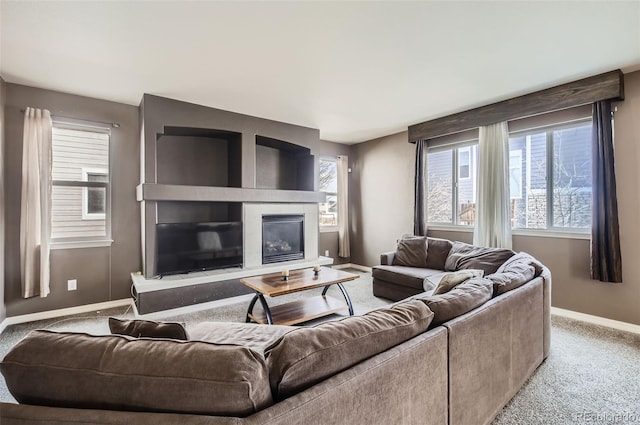 carpeted living area featuring baseboards and a glass covered fireplace