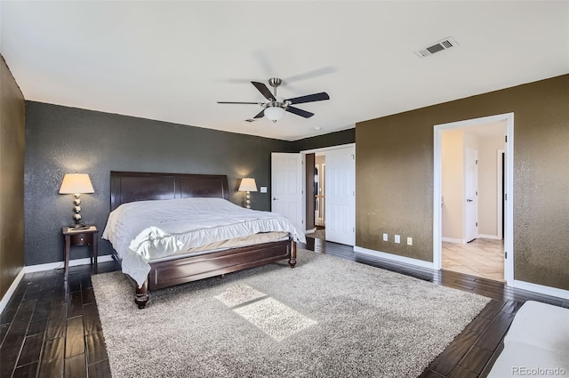 bedroom with visible vents, a textured wall, baseboards, and wood finished floors