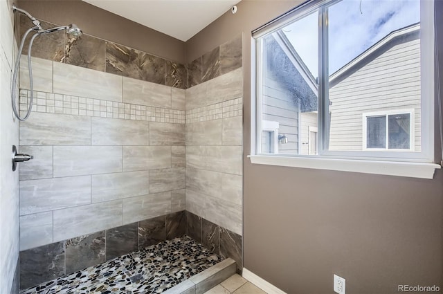 bathroom with a tile shower and baseboards