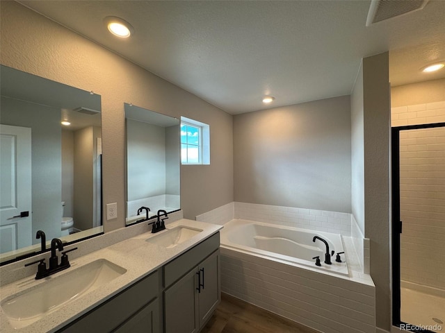 full bathroom with wood-type flooring, toilet, shower with separate bathtub, and vanity