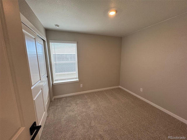 carpeted empty room with a textured ceiling