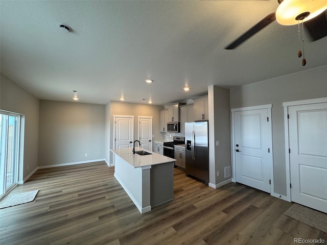 kitchen featuring sink, stainless steel appliances, a center island with sink, dark hardwood / wood-style flooring, and decorative backsplash