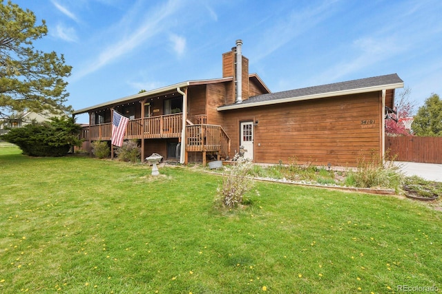 back of house with fence, stairs, a deck, a chimney, and a lawn