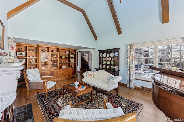 living room featuring beam ceiling, hardwood / wood-style flooring, and high vaulted ceiling