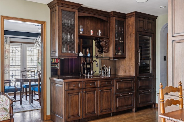 bar featuring dark brown cabinets and dark hardwood / wood-style flooring