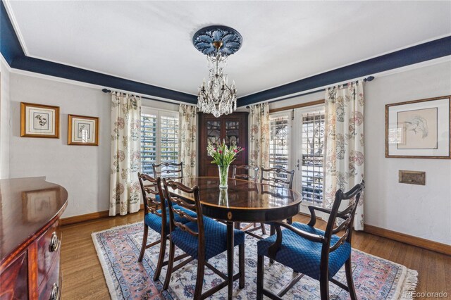 dining area with hardwood / wood-style flooring, plenty of natural light, french doors, and a chandelier