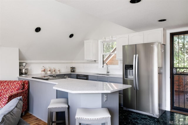 kitchen with a breakfast bar, black appliances, white cabinetry, sink, and kitchen peninsula